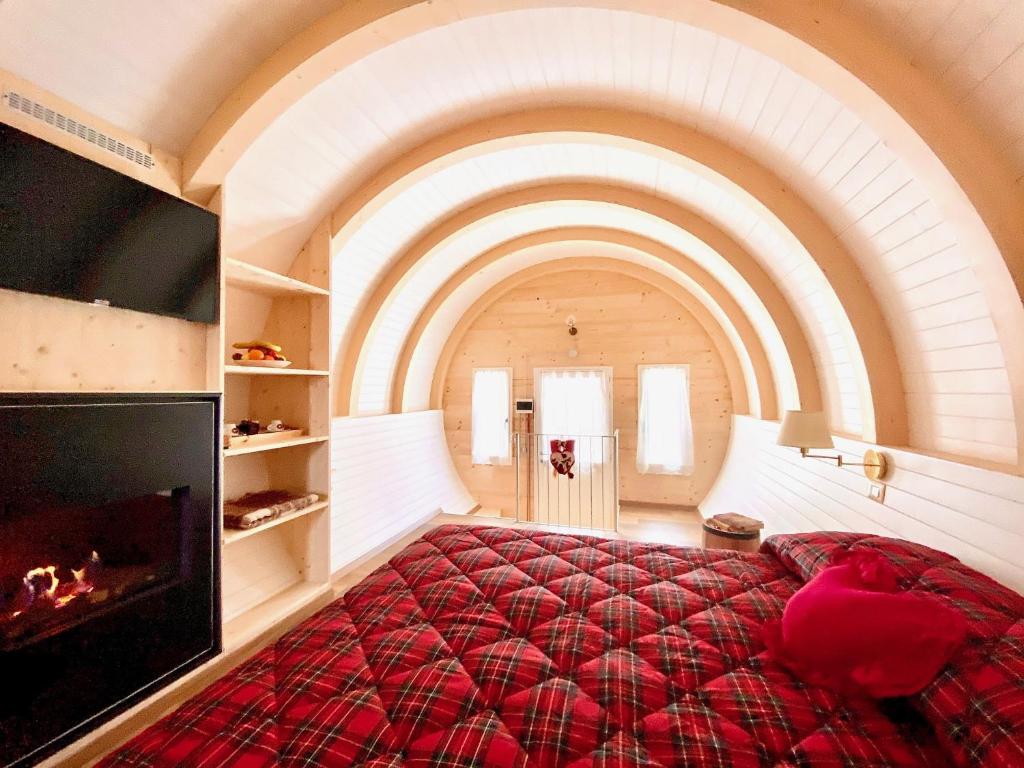una camera con un grande letto rosso e un camino di Glamping Villaggio Parco Dei Castagni 4 stelle a Montecreto
