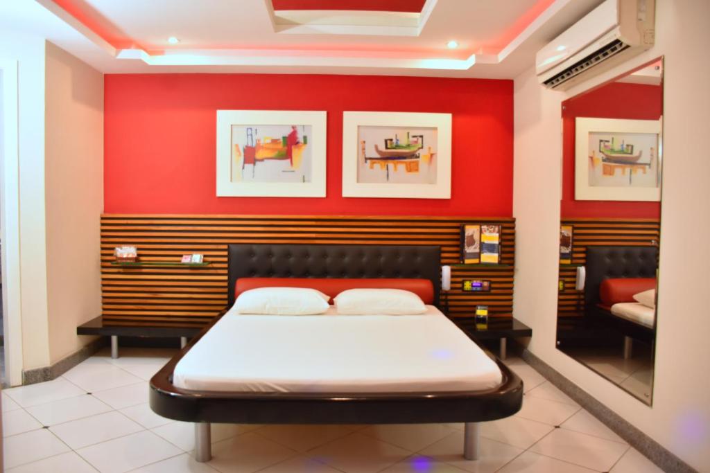 um quarto com uma cama numa parede vermelha em Motel Scala em Salvador