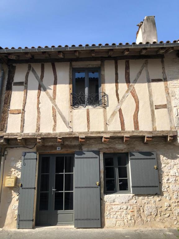 un edificio antiguo con dos puertas y ventanas en Beautiful Eymet Bastide house & courtyard garden, en Eymet
