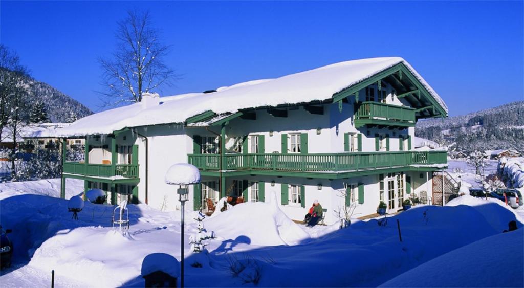 a house with snow on the roof in the snow at Ferienwohnungen Mayer inkl. Chiemgaukarte in Ruhpolding