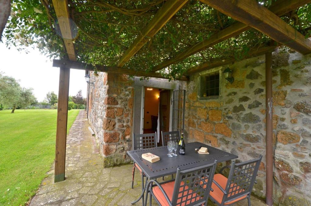 eine Terrasse mit einem Tisch und Stühlen vor einem Steingebäude in der Unterkunft L'Elce in Orvieto
