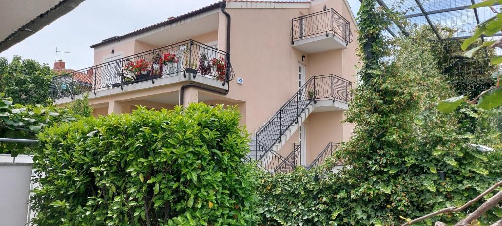 un edificio con balcones y plantas frente a él en Apartmani Tomislav en Krk