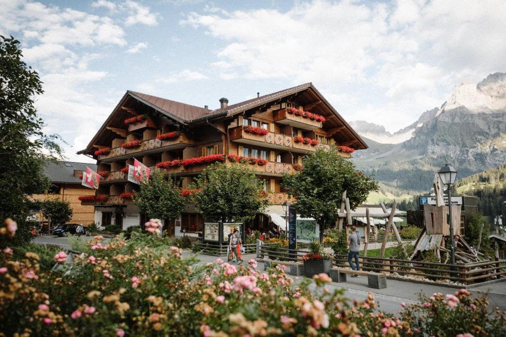 a hotel in the mountains with flowers in front of it at Adler Adelboden in Adelboden