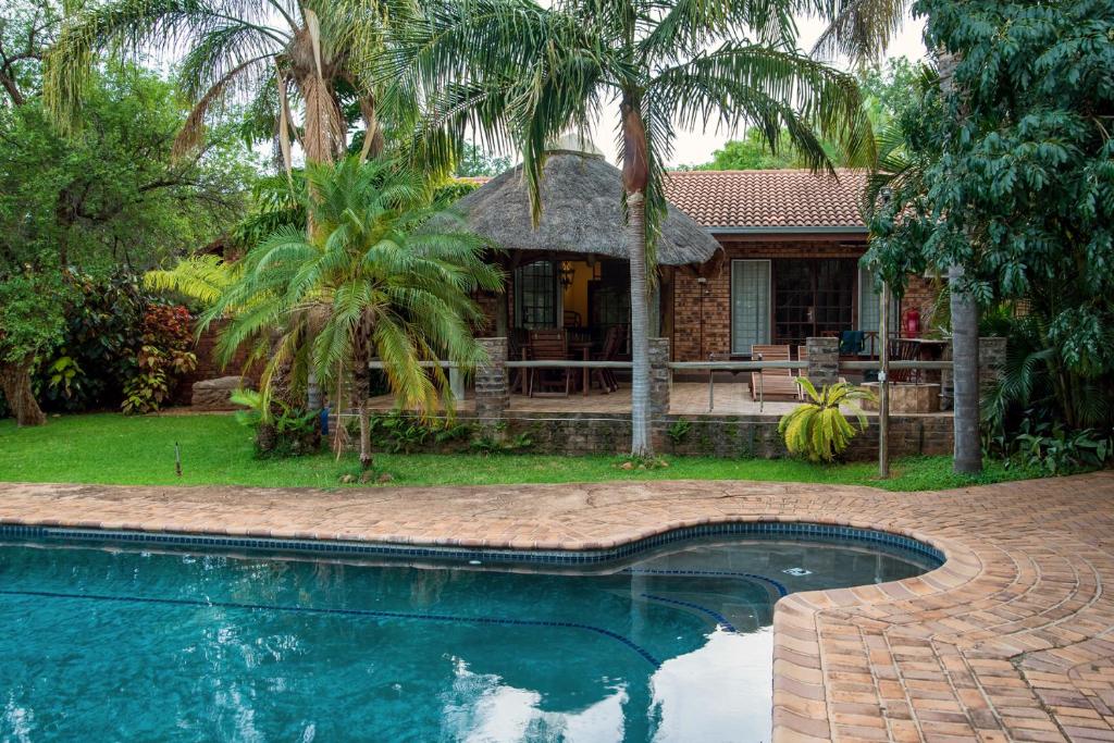 a house with a swimming pool in front of a house at Tamboti House in Malelane