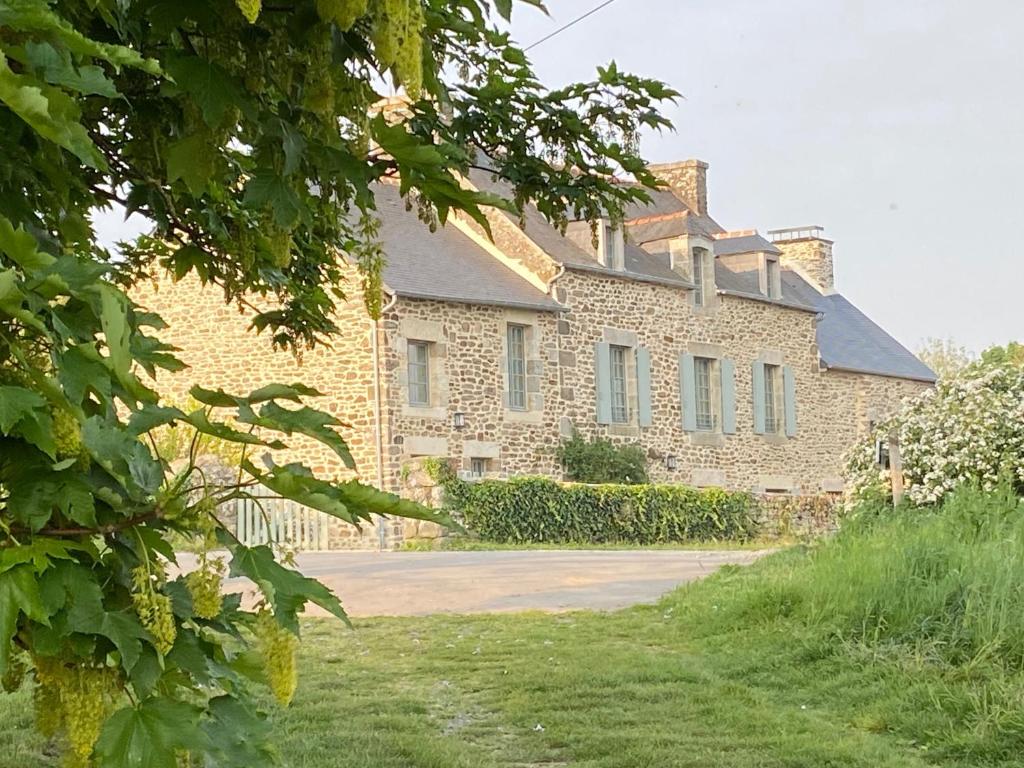 een groot bakstenen gebouw met een tuin ervoor bij les jardins de la Matz in Plouër-sur-Rance