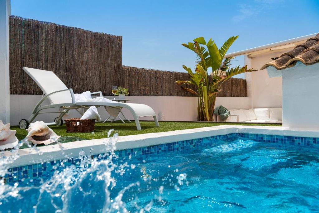 - une piscine dans un jardin avec une table et des chaises dans l'établissement AlohaMundi San Luis, à Séville