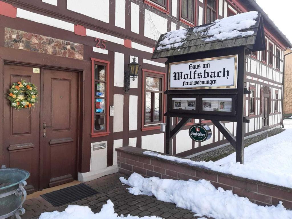 un cartello di fronte a un edificio nella neve di Haus am Wolfsbach Gruppenunterkunft a Zorge