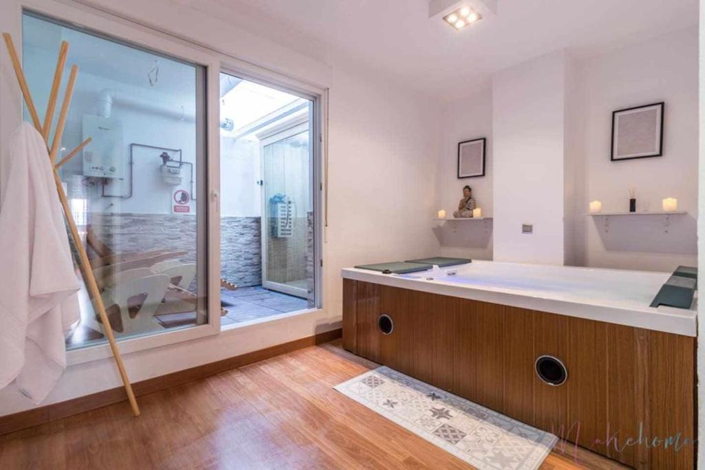 a large bathroom with a tub and a large window at Lujo a tu alcance con spa y garaje pleno centro in Huelva