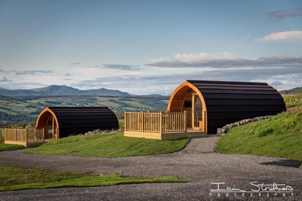 two domed buildings on top of a grassy hill at BenVrackie Luxury Glamping Pet Friendly Pod at Pitilie Pods in Aberfeldy