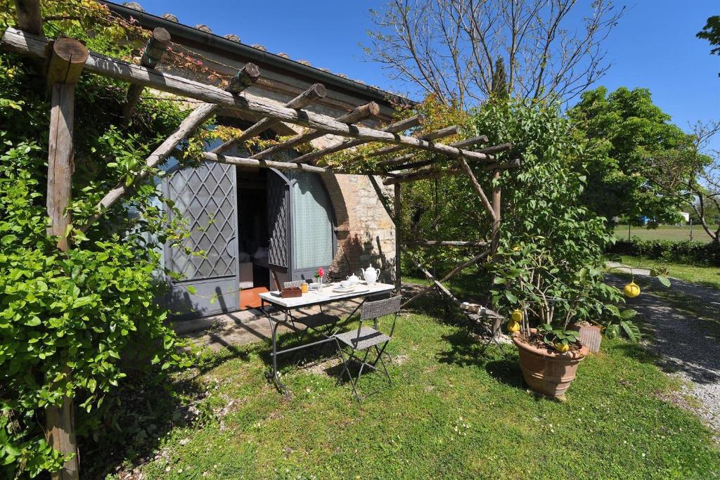 einen Garten mit einer hölzernen Pergola und einem Tisch in der Unterkunft Limonaia in Sovicille