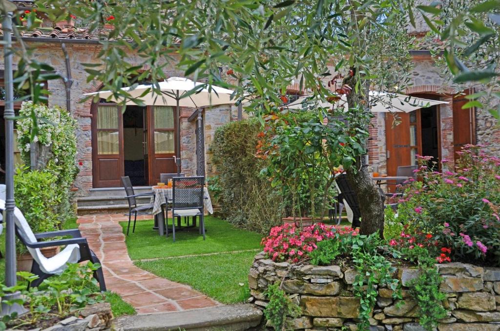 un jardín con mesa, sillas y flores en Francesca 2, en Camaiore