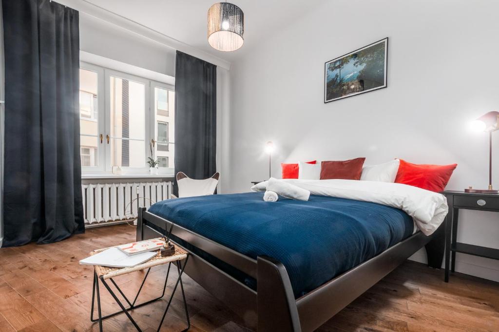 a bedroom with a large bed with blue sheets and red pillows at Apartments Monte Carlo Warsaw by Renters in Warsaw
