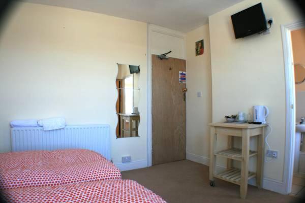 1 dormitorio con cama, mesa y TV en Bayside Guest House en Porthcawl