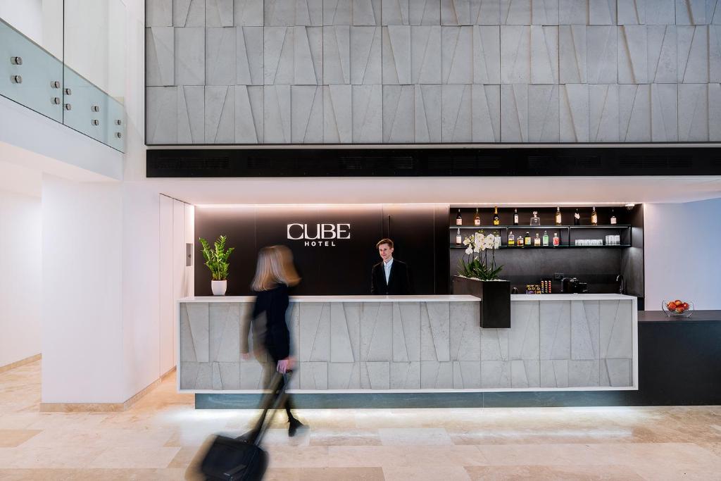 a woman walking in front of a bar with a man at Hotel CUBE Prague in Prague