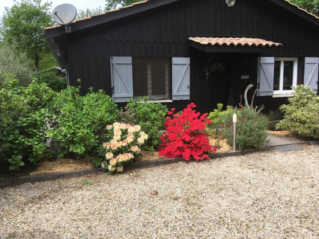 une maison noire avec des fleurs devant elle dans l'établissement Maison De L'amitié, à Lanton