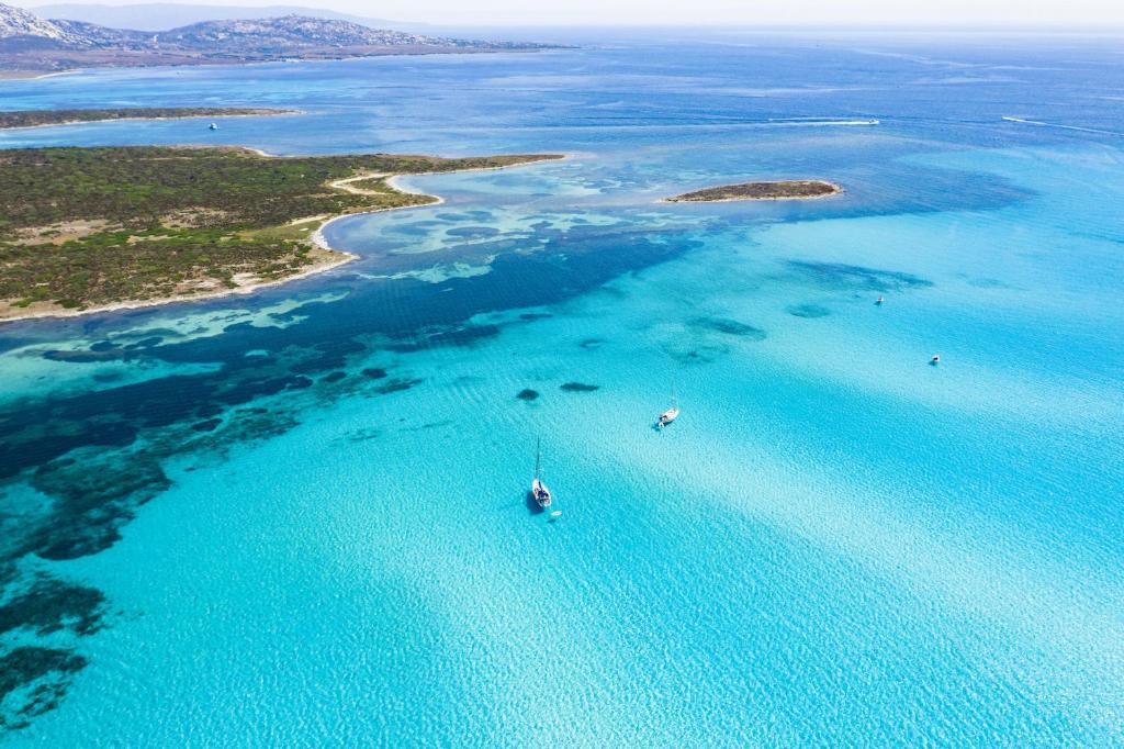 una vista aerea di una barca nell'oceano di Club Esse Roccaruja a Stintino