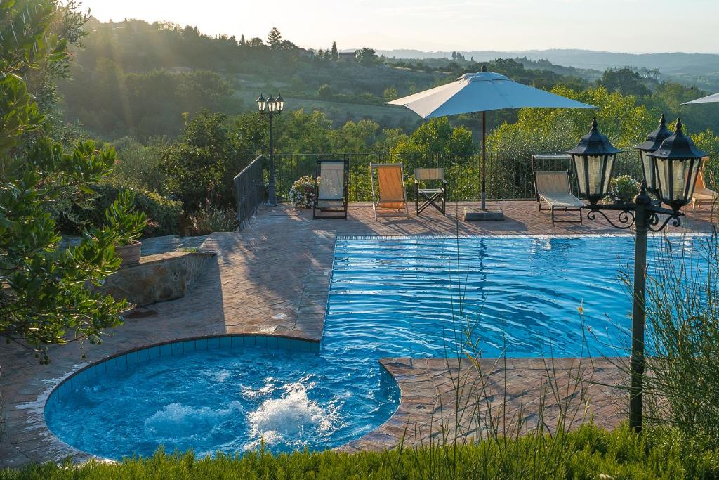 a swimming pool with an umbrella in a yard at Agriturismo I Colli in Montaione