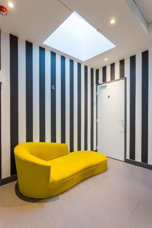 a yellow chair in a room with striped walls at CMG - Champs Elysées Boetie 4DF in Paris