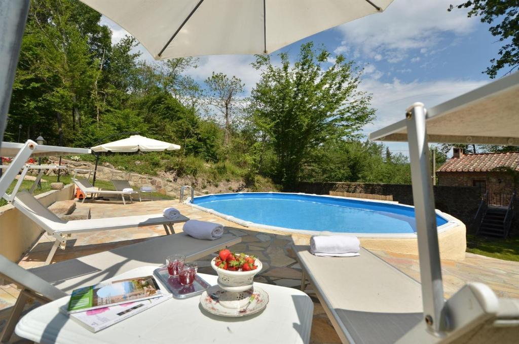 eine Terrasse mit einem Tisch, einem Sonnenschirm und einem Pool in der Unterkunft Mulino del Rigualdo in Roccastrada
