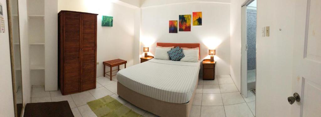 a bedroom with a bed and two lamps and a bathroom at Tropical Apartments Tobago in Scarborough