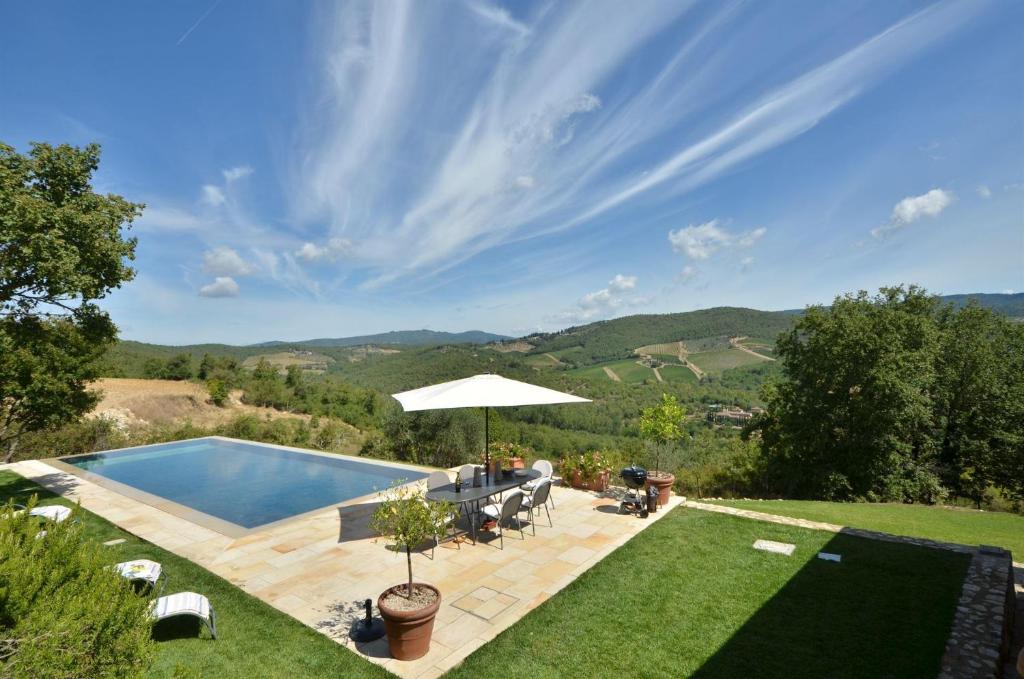 a backyard with a swimming pool and an umbrella at Le Cerreta in Gaiole in Chianti