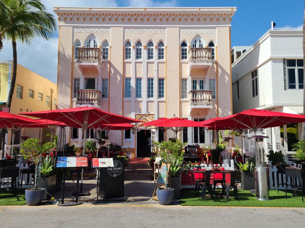 a building with tables and red umbrellas in front of it at 918 SOBE FLATS in Miami Beach