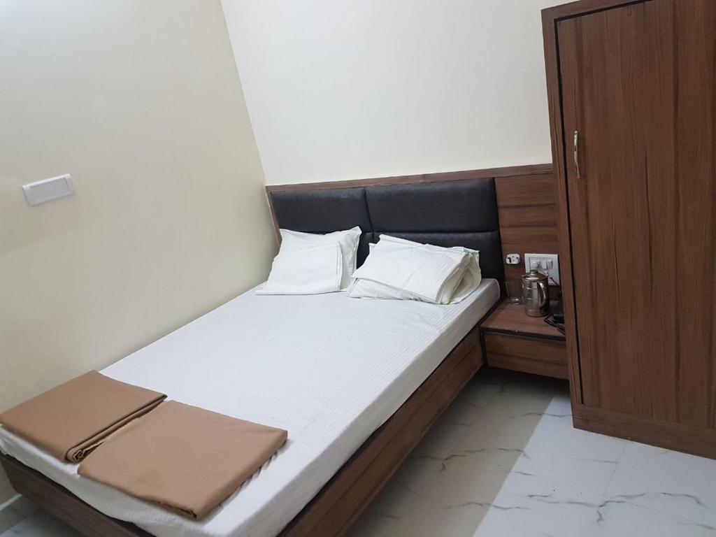Bett mit weißer Bettwäsche und Kissen in einem Zimmer in der Unterkunft K K RENUKA DHARAMSHALA in Haridwar