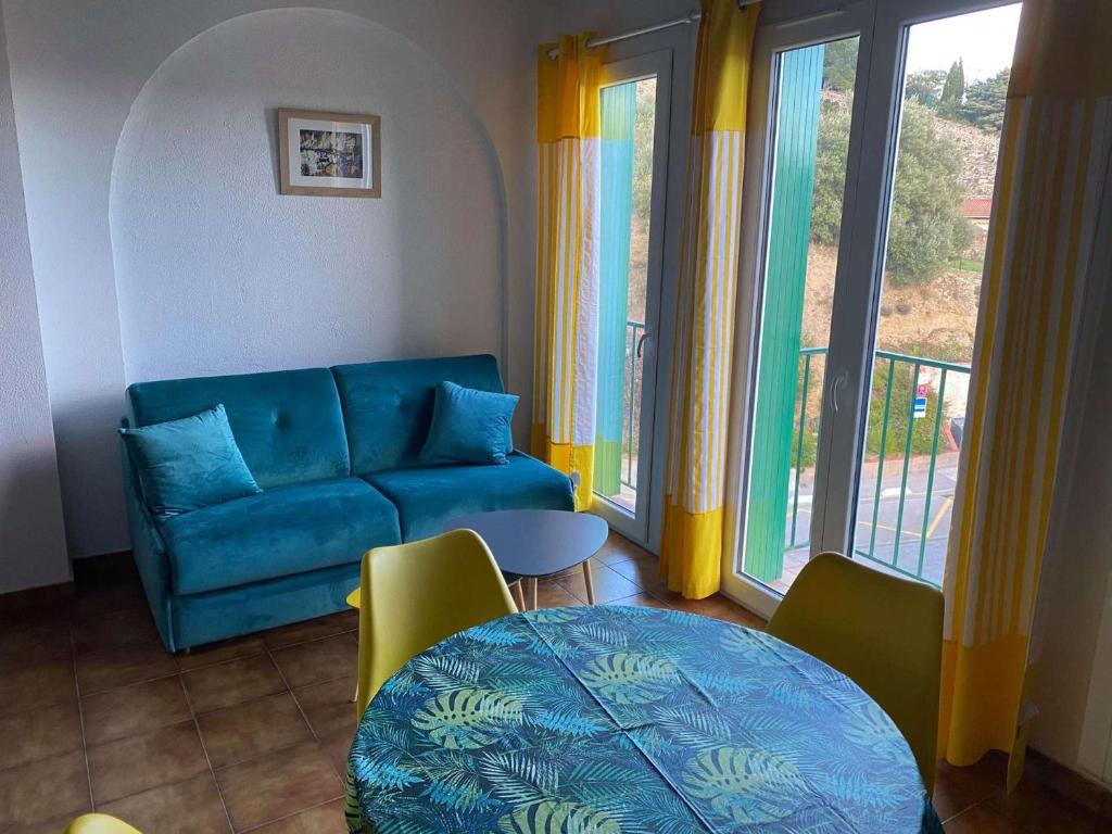 un salon avec un canapé bleu et une table dans l'établissement 4MIR11JAUNE- T2 en DUPLEX idéalement situé pour 4 personnes, à Collioure