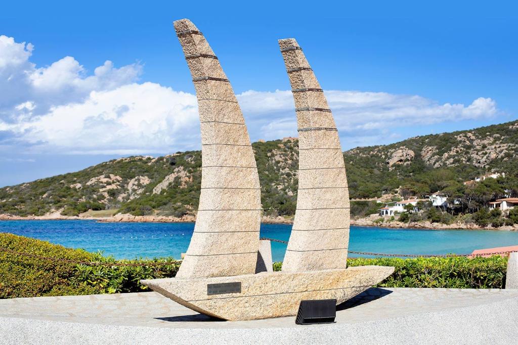 una escultura de piedra de dos torres en una playa en Club Esse Cala Bitta, en Baja Sardinia