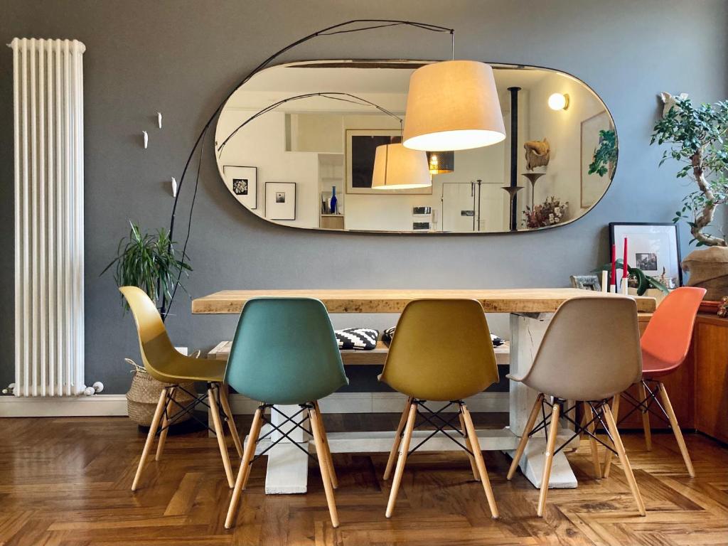 uma sala de jantar com um espelho e quatro cadeiras em Vicolo Folletto Home em Reggio Emilia