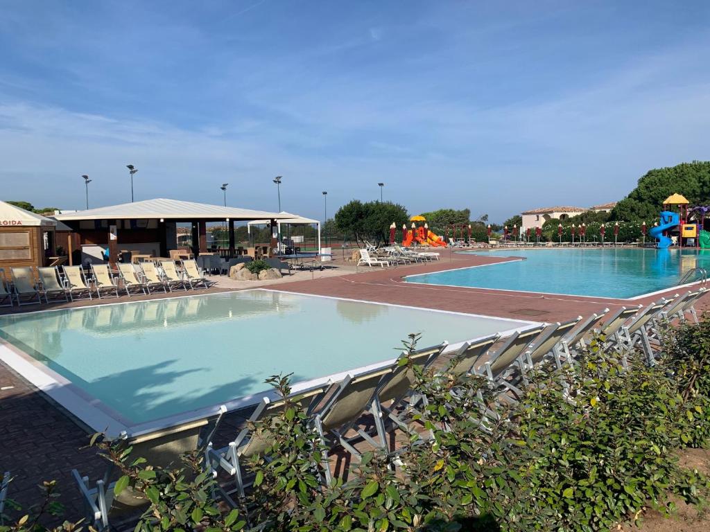 una gran piscina con sillas y un parque infantil. en Club Esse Gallura, en Aglientu