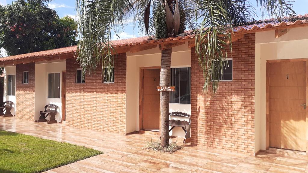 ein Backsteinhaus mit einer Palme davor in der Unterkunft Pousada recantoceccataratas in Foz do Iguaçu