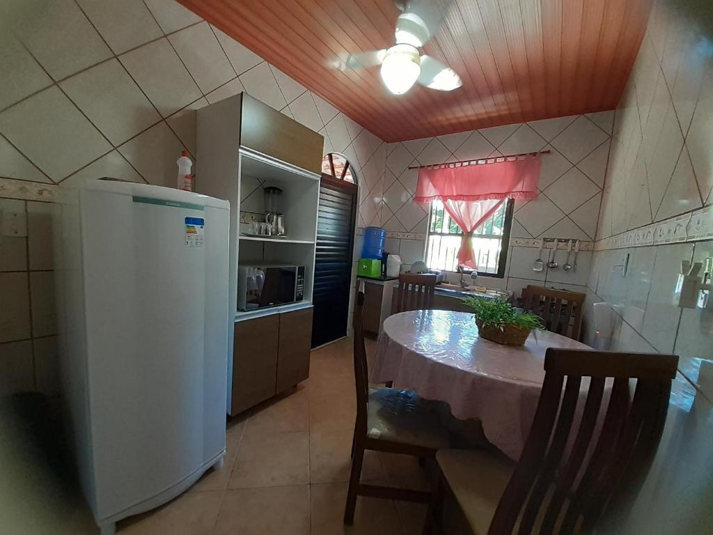 a kitchen with a table and a white refrigerator at Casinha do Trapiche in Penha