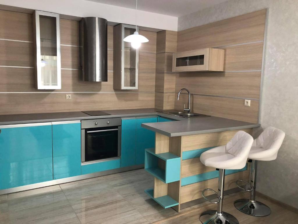 a kitchen with blue cabinets and a counter with stools at Апартамент Анели in Pomorie