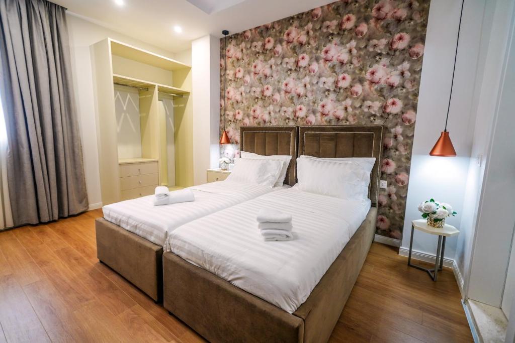 a bedroom with a large bed with a floral wall at Rama's Hotel in Tirana