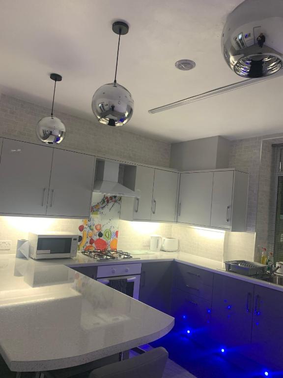 una cocina con armarios blancos y luces azules en Travis House Three Luxury Modern Living free WiFi en Burnley