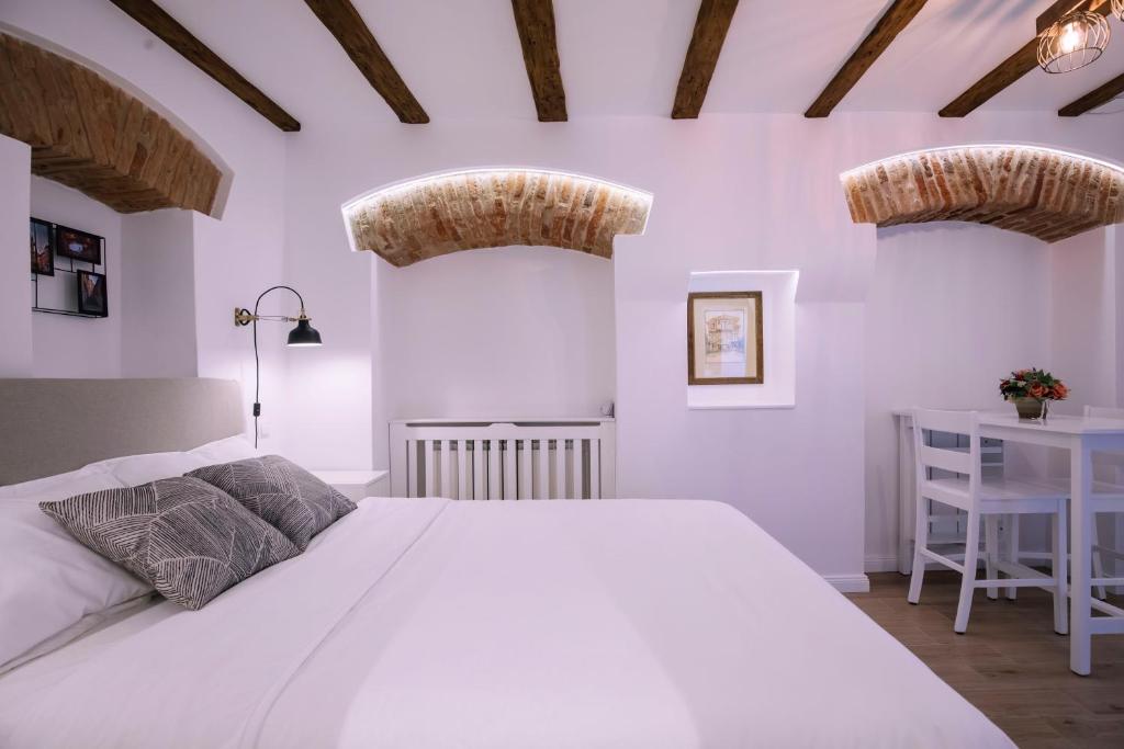 a white bedroom with a large bed and a desk at Chic Central Studio in Sibiu