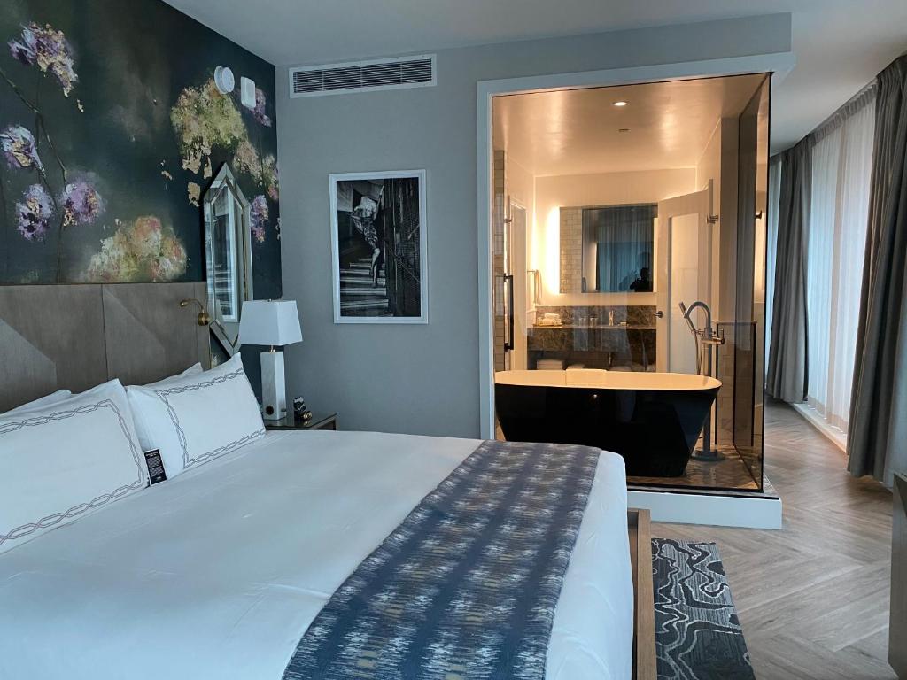 a bedroom with a large bed and a bath tub at EXchange Hotel Vancouver in Vancouver