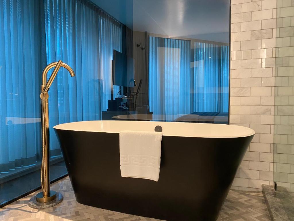 a bath tub in a bathroom with blue curtains at EXchange Hotel Vancouver in Vancouver