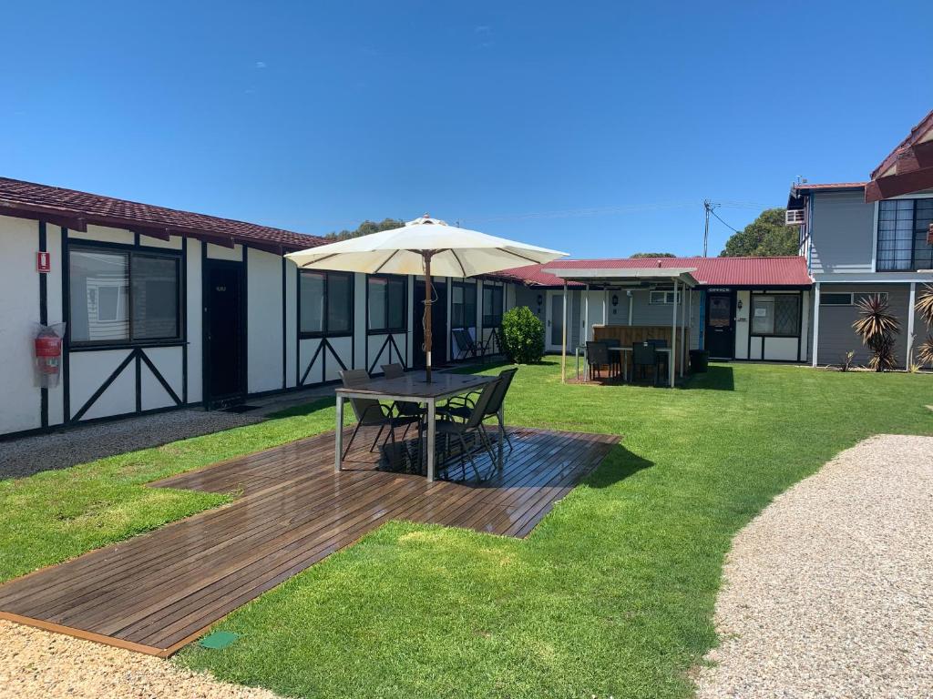 a wooden deck with a table and an umbrella at Robe Nampara Cottages in Robe