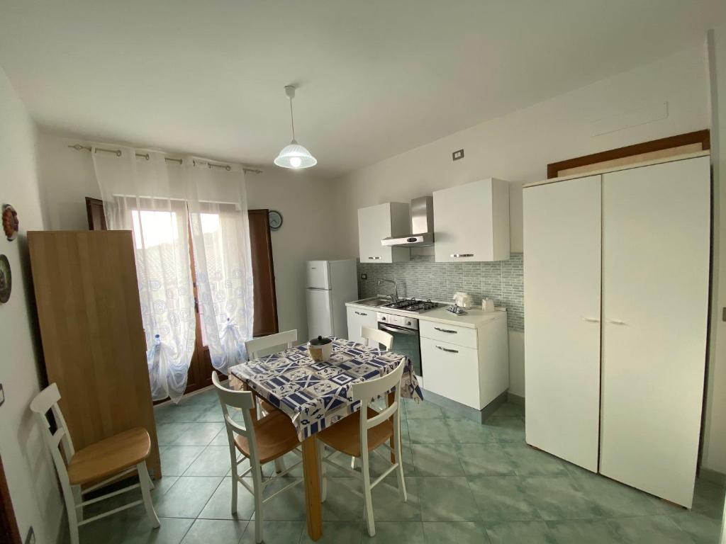 una cucina con tavolo e sedie e una cucina con armadietti bianchi di Petra Marina Maris a Pisciotta