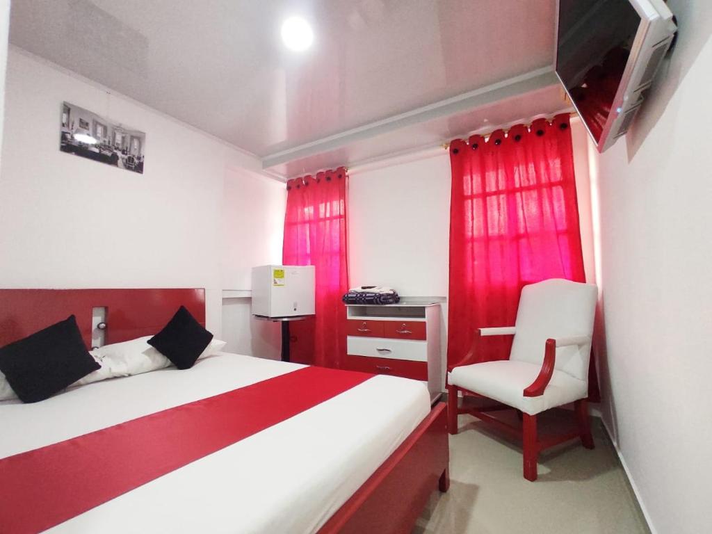 um quarto com uma cama vermelha e branca e uma cadeira em Hotel Casablanca Cañaveral em Floridablanca