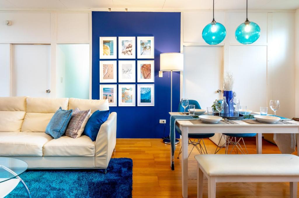 sala de estar con sofá blanco y pared azul en Deluxe Room 130平米 URUMAHOTEL, en Uruma
