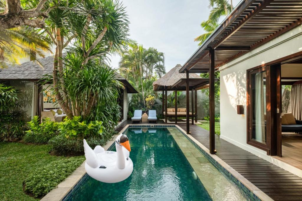 a swimming pool with two swans in a house at Le Jardin Villas Seminyak in Seminyak