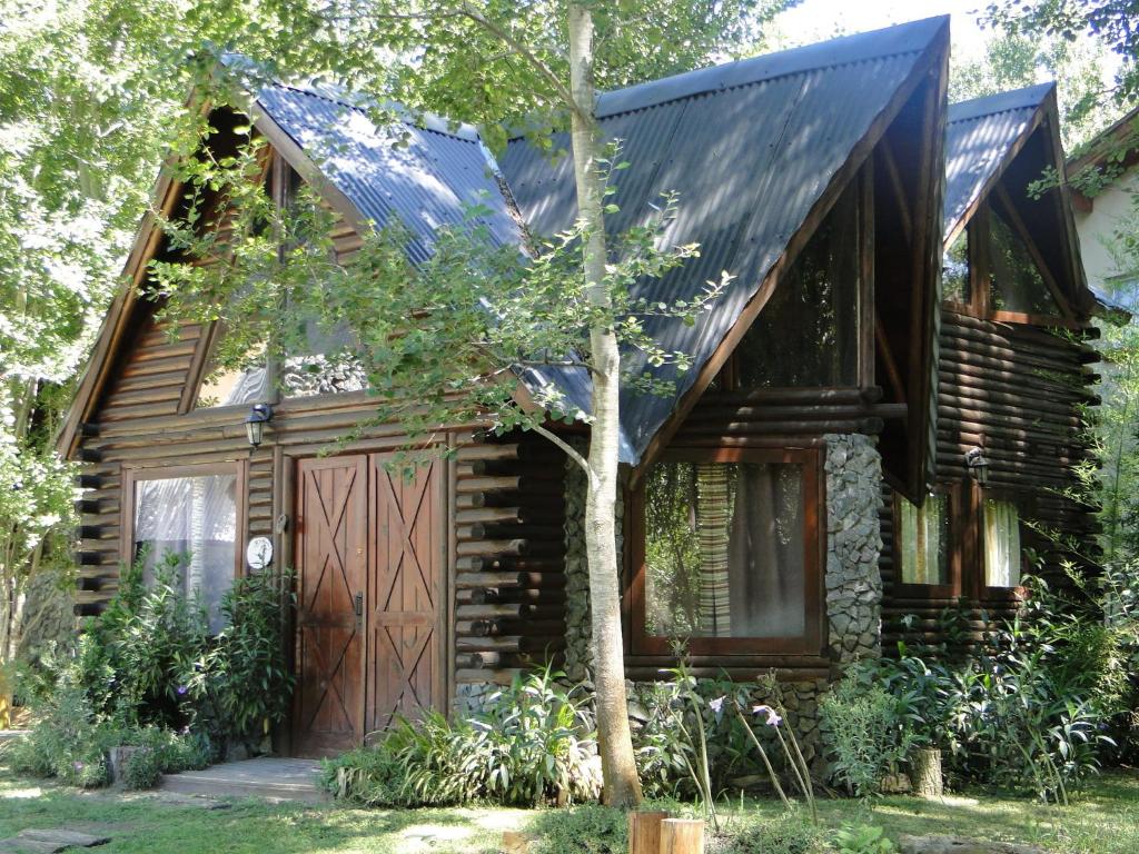 ein Blockhaus mit einer Garage und einem Baum in der Unterkunft Bosques del Este in Costa del Este