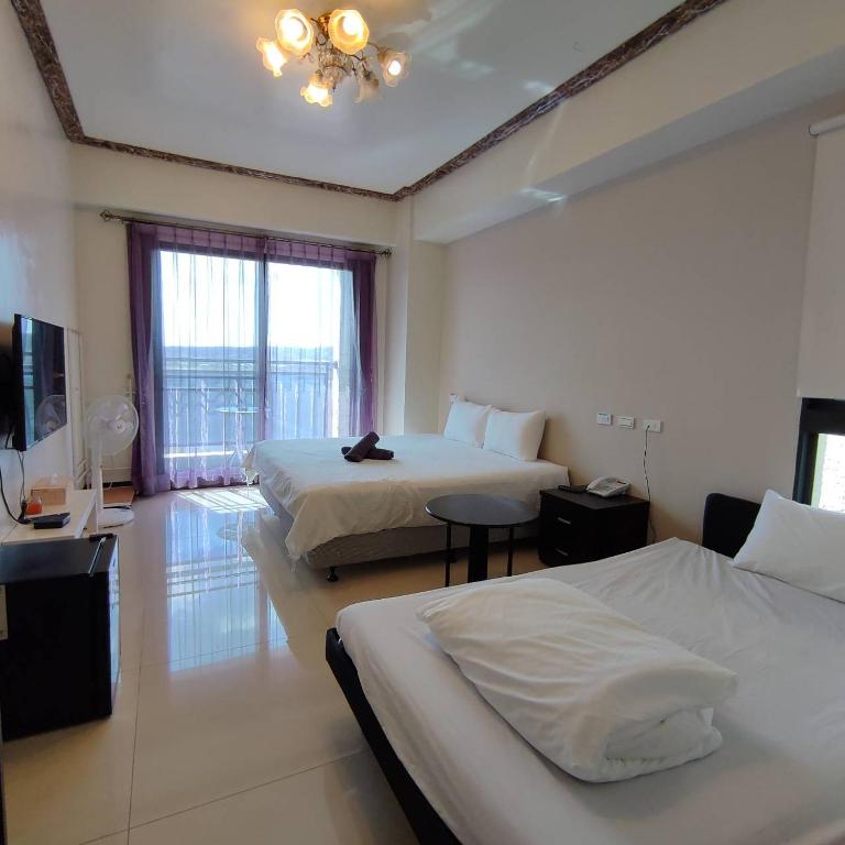 a hotel room with two beds and a television at 墾丁秋莊會館 附限量停車位 不保證有位置 無法事先預留 背包房無車位 預訂後記得加Line聯繫 in Hengchun