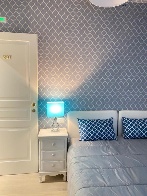 a bedroom with a bed and a lamp on a night stand at Hotel La Maison Delle Terme in Tivoli Terme
