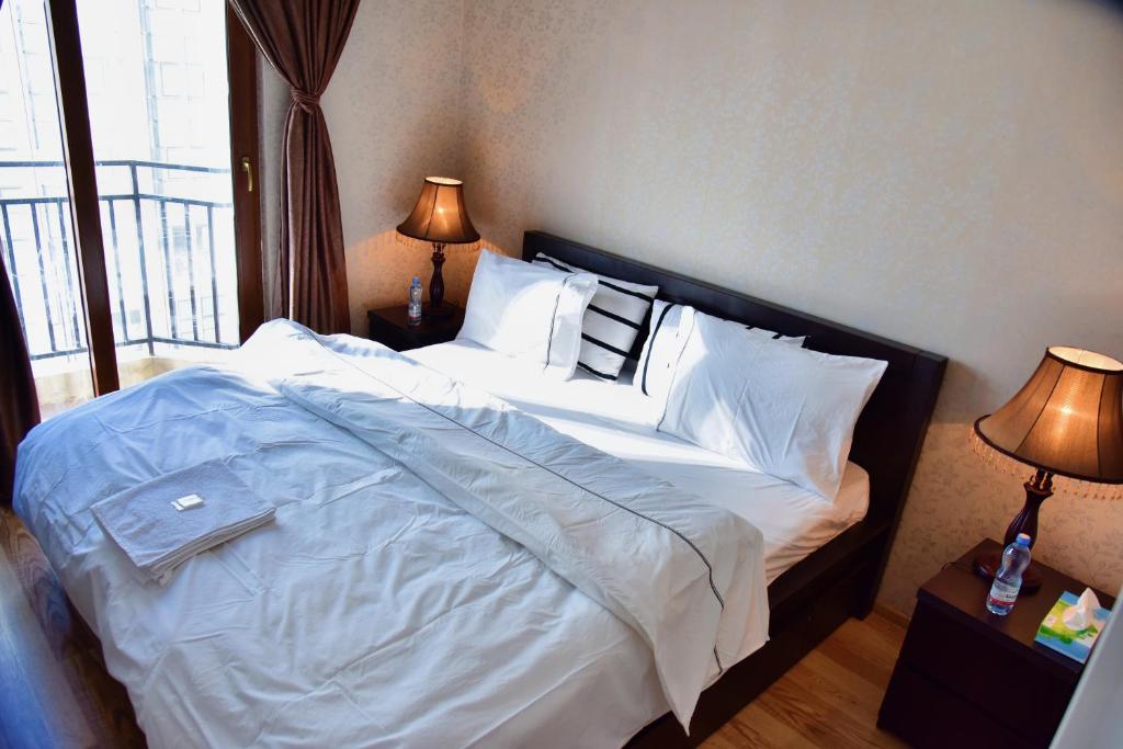 a bedroom with a large bed with white sheets and pillows at Aden Apartments in Tbilisi City