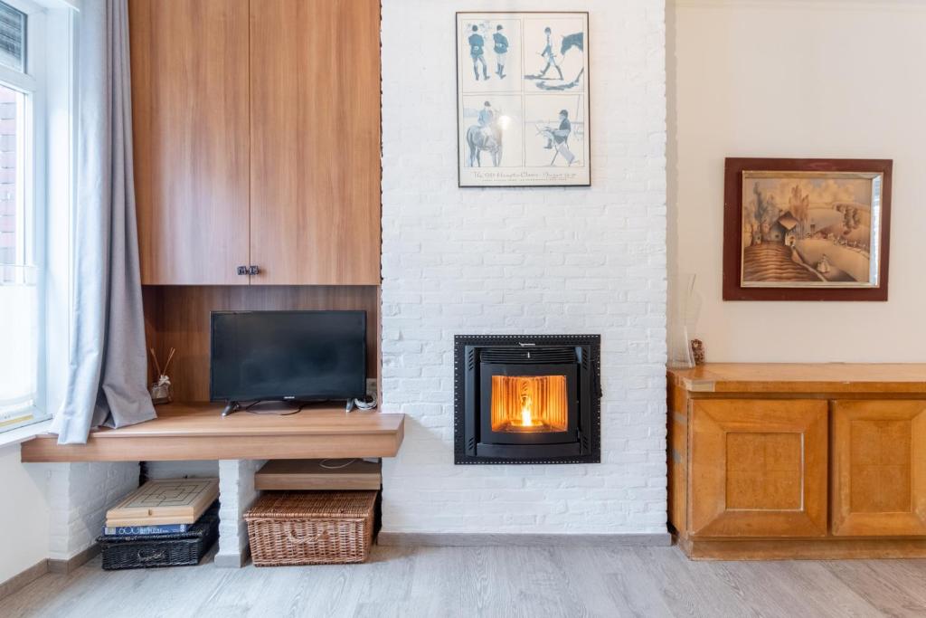 Una sala de estar con chimenea y televisión. en Bruges Holiday Home, en Brujas