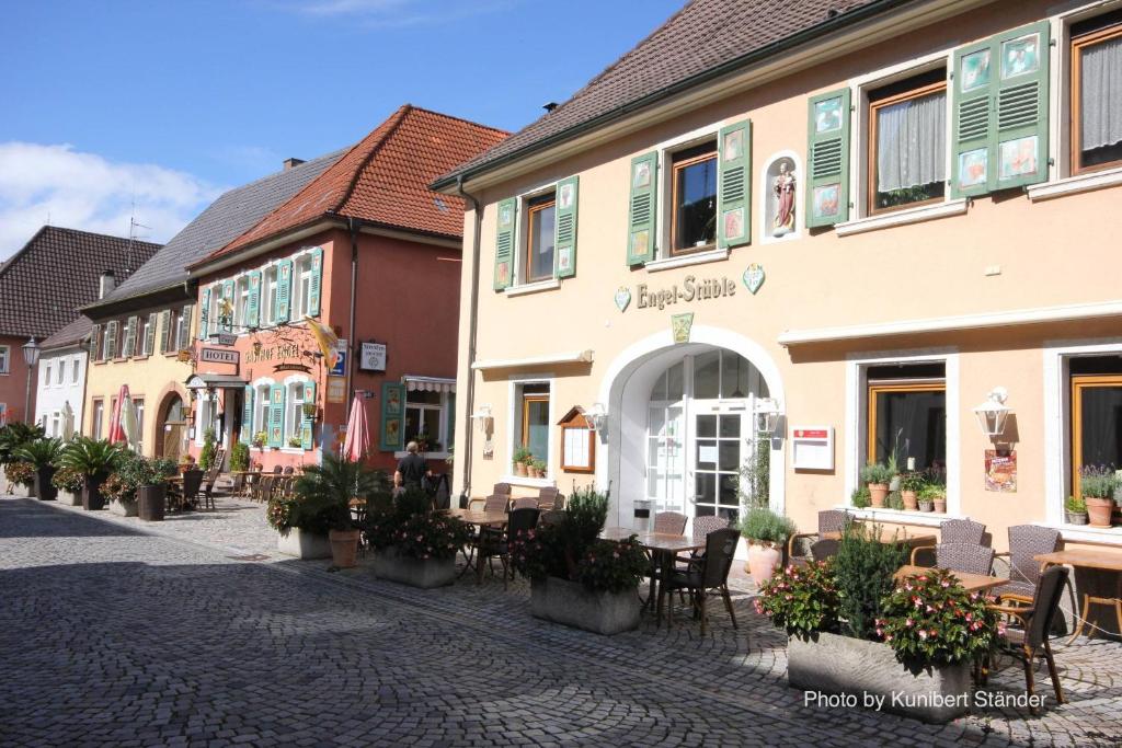 une rue pavée avec des tables et des chaises en face des bâtiments dans l'établissement Hotel Engel, à Endingen am Kaiserstuhl